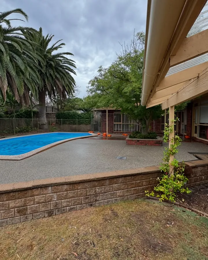 Concrete pool surround completed beside a brick retaining wall